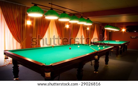 Interior of a club having billiard tables illuminated with lights