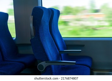 Interior Of Commuter Passenger Train Car, Row Of Chairs And A Motion-blurred Landscape Outside The Window
