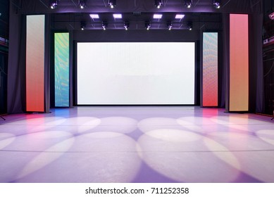 Interior of a conference concert hall or theatre with LED screen on scene and red seats