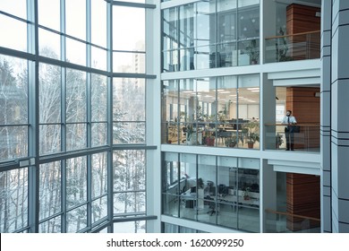 Interior of contemporary multi-floor business center with large windows and many offices in front of them
