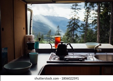 Interior of converted camper van or camping RV kitchen, coffee kettle and grinder stand on indoor table. Concept vanlife on the road, outdoor camp vibes for digital nomads