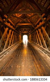 Interior of Corbin wooden bridge, in Newport, New Hampshire, showing wood peg, cross beam and truss structure, and shiny wet deck from rainy day. 