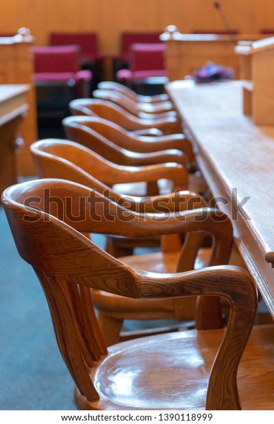 Interior of a courtroom with an attorney,\
defence, counsel or plaintive bench and chairs. The empty long\
wooden table has microphones.The wooden furniture is old and worn\
with a disciplined\
atmosphere