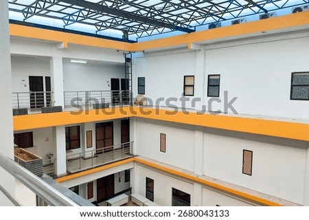 Interior courtyard of a simple multi-story building with white walls and bright yellow accents