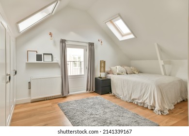 The interior of a cozy bedroom with slanted windows on the ceiling and a carpet on the floor