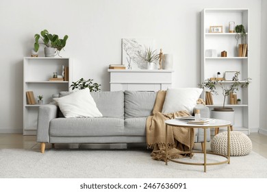 Interior of cozy living room with grey sofa and reed diffuser on coffee table