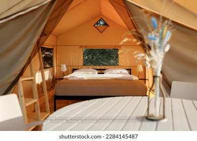 Interior of Cozy open glamping tent with light inside during sunset. Luxury camping tent for outdoor summer holiday and vacation. Lifestyle concept - Powered by Shutterstock