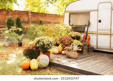 Interior cozy yard with fall flowers chrysanthemums potted and orange pumpkins decorated for Halloween. Exterior wooden porch house with basket with plants, autumn decorations, lanterns and guitar.  - Powered by Shutterstock