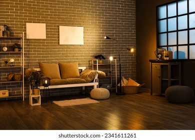 Interior of dark living room with couch, shelving units and glowing lamps - Shutterstock ID 2341611261