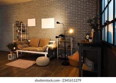 Interior of dark living room with couch, shelving units and glowing lamps - Shutterstock ID 2341611279