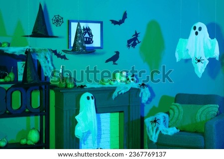 Interior of dark living room decorated for Halloween with armchair and mantelpiece