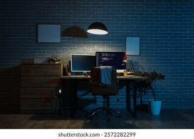 Interior of dark programmer's office with workplace and glowing lamp