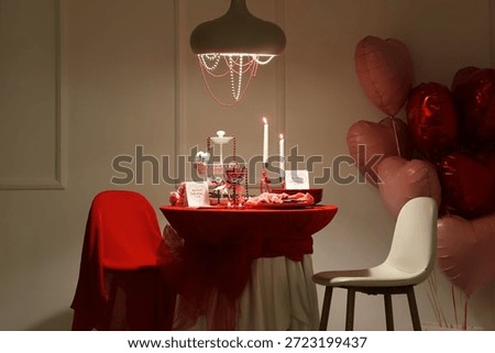 Interior of dark room with dining table set for Valentine's Day, balloons and glowing lamp