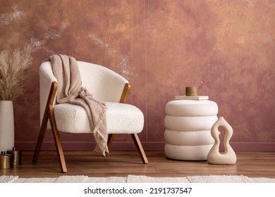 Interior design of aesthetic and elegant room with white boucle armchair, modern pouf, vase with dried flowers and personal accessories. Stylish home decor. Template. Copy space. Grunge wall. 