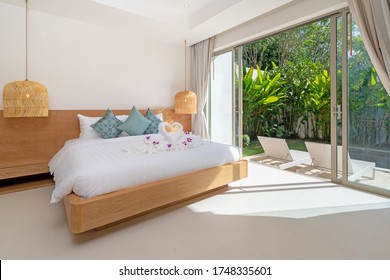 Interior design of bedroom in luxury and modern style pool villa feature a pool view, green garden, sunbed or sunlounger on pool terrace,  blue cushion on bed and hanging lamp and sliding door - Powered by Shutterstock