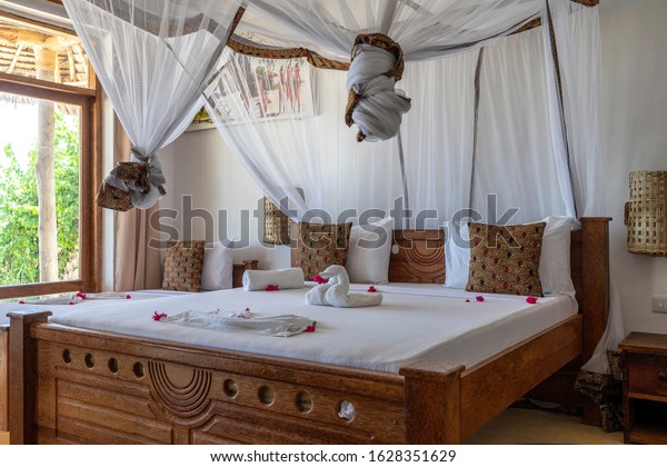 Interior design decor furnishing of luxury show\
home holiday villa bedroom with four poster bed. Interior design of\
the tropical villa on the sea on the island of Zanzibar, Tanzania,\
East Africa