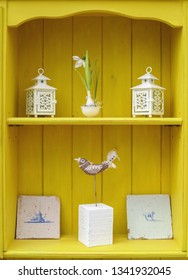 Interior Design Display. Close Up Detail Of Yellow Shabby Chic Welsh Dresser Shelves With Tiles, Lanterns, Bird And Flower Ornaments. Vertical.