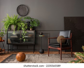 Interior design of elegant living room interior with mock up poster frame, leather armchair, glass sideboard, plants, pillows, rug, black wall, books and personal accessories. Home decor. Template. 