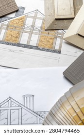 Interior design flat lay with floor plans, fabric swatches, wood samples and drafting tools on designer workspace