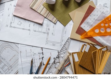 Interior design flat lay with floor plans, fabric swatches, wood samples and drafting tools on designer workspace