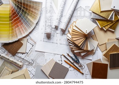 Interior design flat lay with floor plans, fabric swatches, wood samples and drafting tools on designer workspace