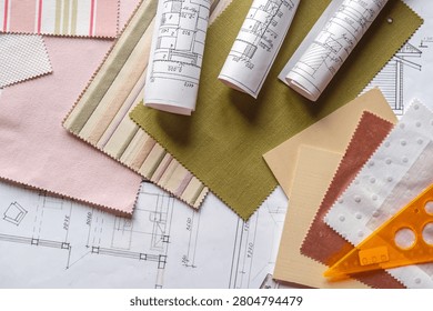 Interior design flat lay with floor plans, fabric swatches, wood samples and drafting tools on designer workspace