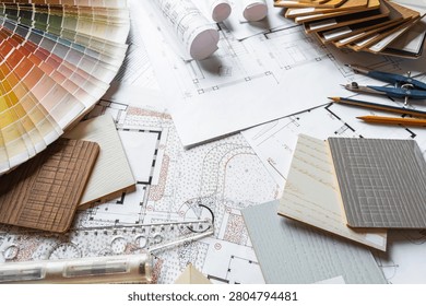 Interior design flat lay with floor plans, fabric swatches, wood samples and drafting tools on designer workspace