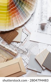 Interior design flat lay with floor plans, fabric swatches, wood samples and drafting tools on designer workspace