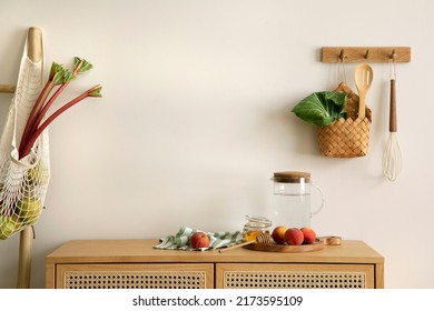Interior design of kitchen space with copy space, rattan commode,  ladder, rhubarb, vegetables, food and kitchen accessories in modern home decor.  Template. 