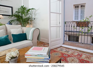 Interior Design Lifestyle Of A Home Living Room With White Sofa And Cushions, Interior View. House Indoors With Carpets And Open French Doors Balcony. Tranquil And Aspirational Lifestyle Home Space.