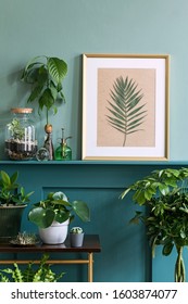 Interior design of living room with gold mock up photo frame on the green shelf with beautiful plants in different hipster and design pots. Elegant personal accessories. Home jungle. Template. 