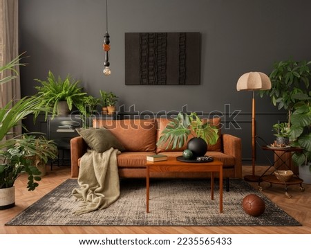 Interior design of living room interior with mock up poster frame, brown sofa, plants, wooden coffee table, lamp, ball, stylish rug, plaid, pillows and personal accessories. Home decor. Template. 