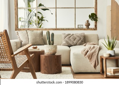 Interior design of living room with stylish modular beige sofa, wooden coffee tables, plants, pillows, plaid, neutral room divider, decoration and elegant accessories. Modern home decor. Template.