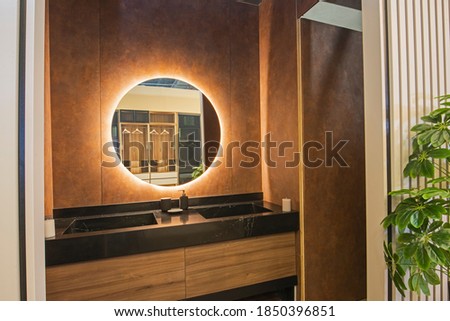 Interior design of a luxury show home bathroom with twin sinks and round mirror