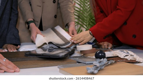 Interior design professionals collaborating at table, reviewing wood, fabric, and tile samples while planning comprehensive renovation strategy. Selection of materials for interior design