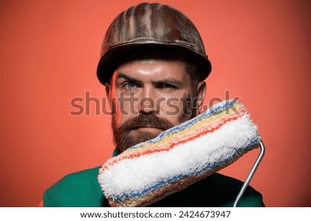 Interior design, repair, home renovation and painting concept. Portrait male painter or decorator with paint roller. Professional painter worker. Bearded man in hard hat with paintroller. Painter man.