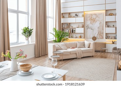 interior design spacious bright studio apartment in Scandinavian style and warm pastel white and beige colors. trendy furniture in the living area and modern details in the kitchen area. - Shutterstock ID 1918121639