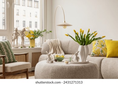 Interior design of spring living room with design sofa, furniture, vase with tulips, easter decorations, pillows and personal accessories. Home decor. Template. Easter holidays.