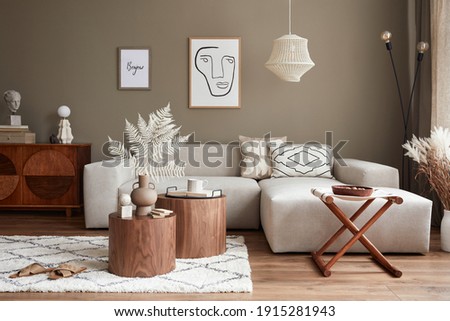 Interior design of stylish living room with modern neutral sofa, furniture, mock up poster farmes, dried flowers in vase, coffee tables, decoration and elegant personal accessories in home decor. 