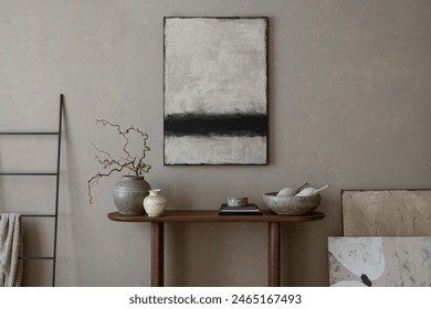 Interior design of warm living room interior with mock up poster frame, wooden consola, black ladder, gray bowl, beige wall, vase with branch and personal accessories. Home decor. Template.