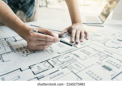 Interior designer or architect reviewing blueprints and holding pencil drawing on desk at home office. - Shutterstock ID 2160273481