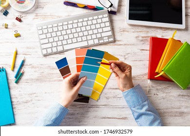 Interior Designer Choosing Colors From Swatches At Wooden Desk. Office Workplace With Computer Keyboard. Selection Of Color Palette For Design. Professional House Renovation And Interior Redesign.