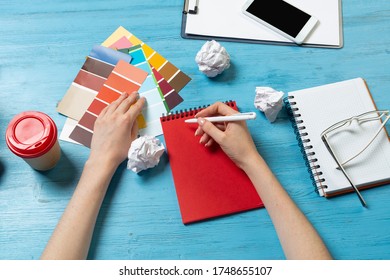 Interior Designer Choosing Colors From Swatches At Blue Wooden Desk. Office Workplace With Computer Keyboard. Selection Of Color Palette For Design. Professional House Renovation And Interior Redesign