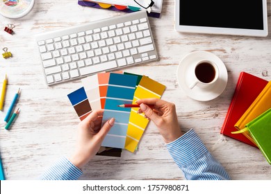 Interior Designer Choosing Colors From Swatches At Wooden Desk. Office Workplace With Computer Keyboard. Selection Of Color Palette For Design. Professional House Renovation And Interior Redesign.