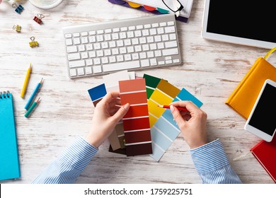 Interior Designer Choosing Colors From Swatches At Wooden Desk. Office Workplace With Computer Keyboard. Selection Of Color Palette For Design. Professional House Renovation And Interior Redesign.