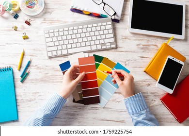 Interior Designer Choosing Colors From Swatches At Wooden Desk. Office Workplace With Computer Keyboard. Selection Of Color Palette For Design. Professional House Renovation And Interior Redesign.