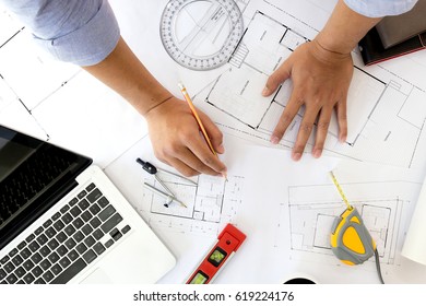 Interior designer discussing data and digital tablet and computer laptop with business document and graphics design diagram on wooden desk as concept