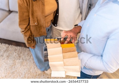 Interior designer presenting fabric samples to couple, helping them choose upholstery for new furniture in a home improvement store