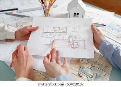 Interior designers working on color hand drawings of a kitchen interior at work place. Photo of young designers work concept