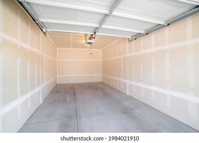 Interior Of A Detached Garage With Open Automatic Single Door. Inside A Single Garage With Unfinished Walls, Concrete Flooring And One Piece White Garage Door On Top.